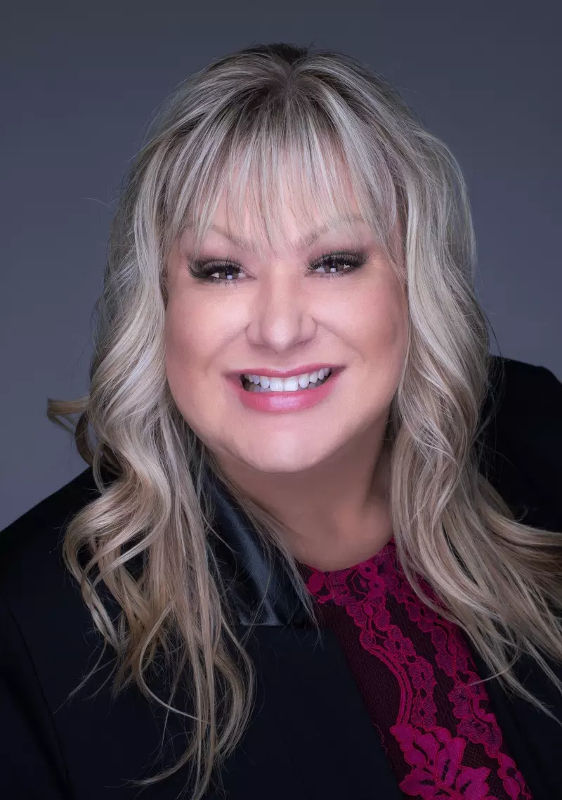 a woman with blonde hair and a black jacket smiles for the camera