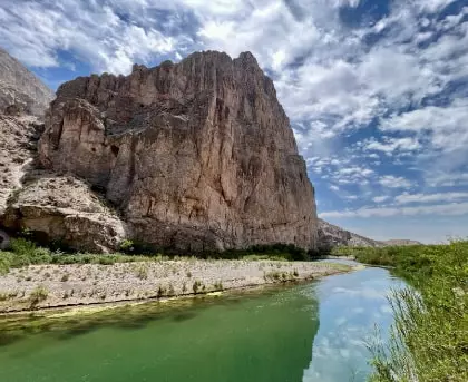 a river running through a canyon with a mountain in the background