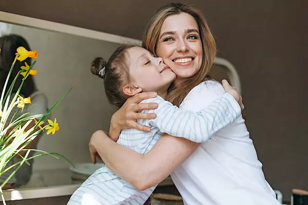 a little girl in striped pajamas hugging her smiling mother