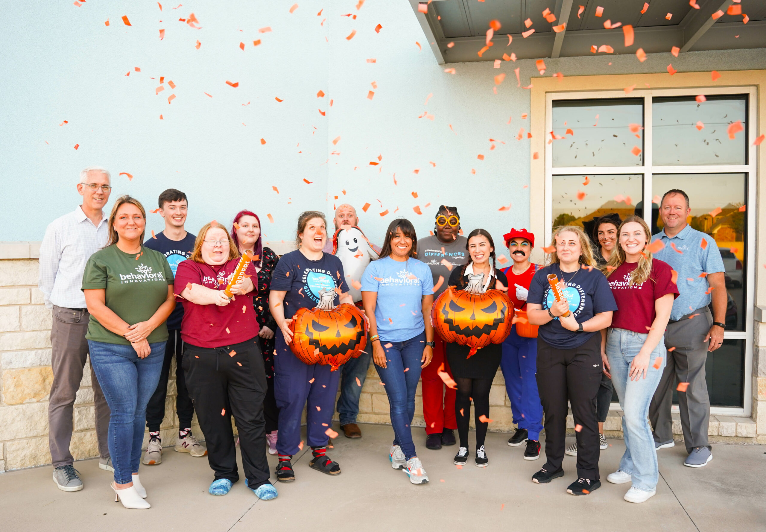 a group of people standing in front of a building wearing halloween shirts