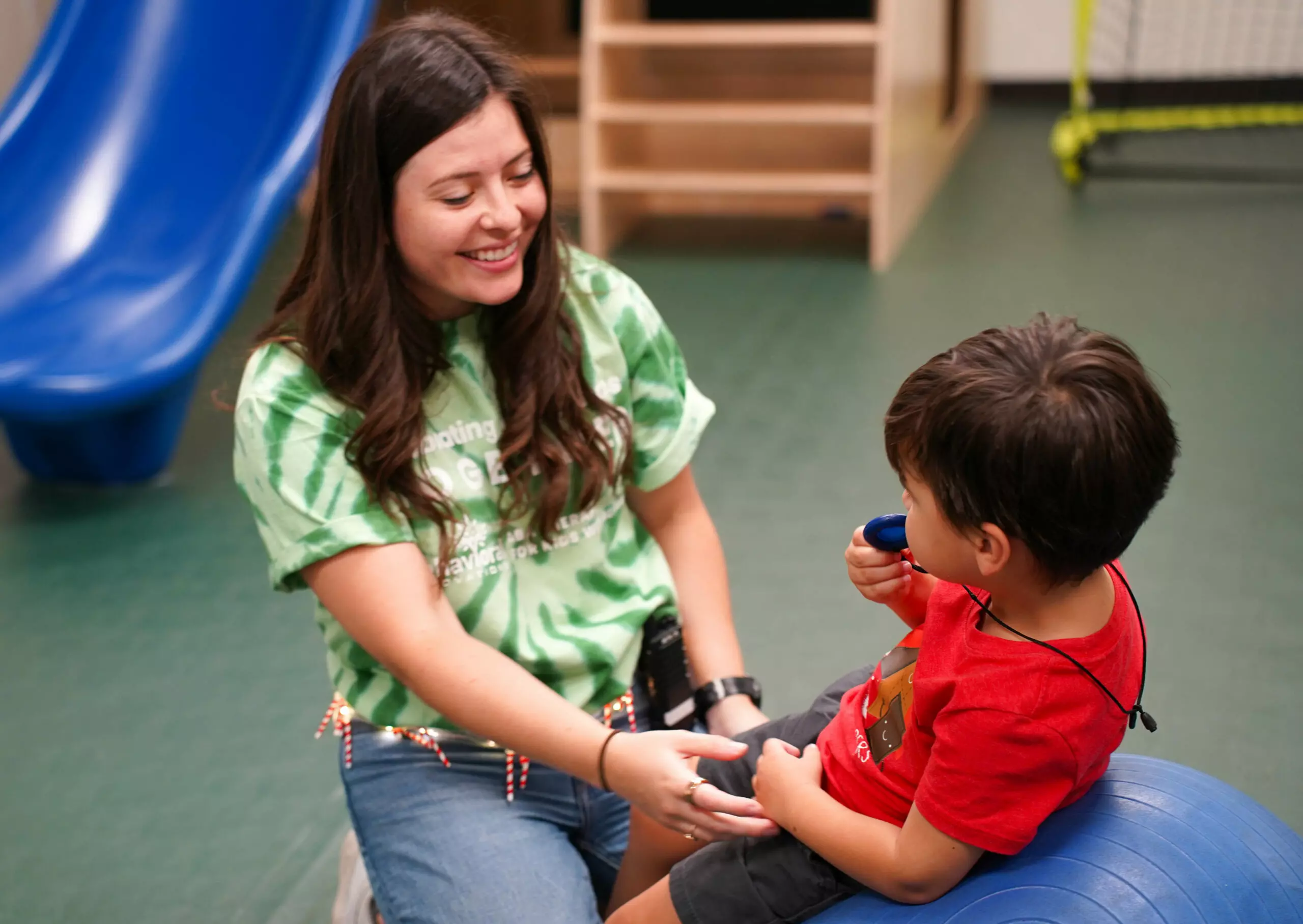a woman wearing a green shirt that says ' teaching ' on it