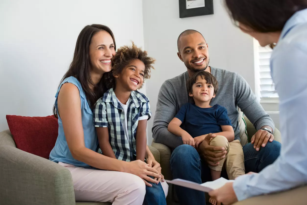a family is sitting on a couch talking to a woman